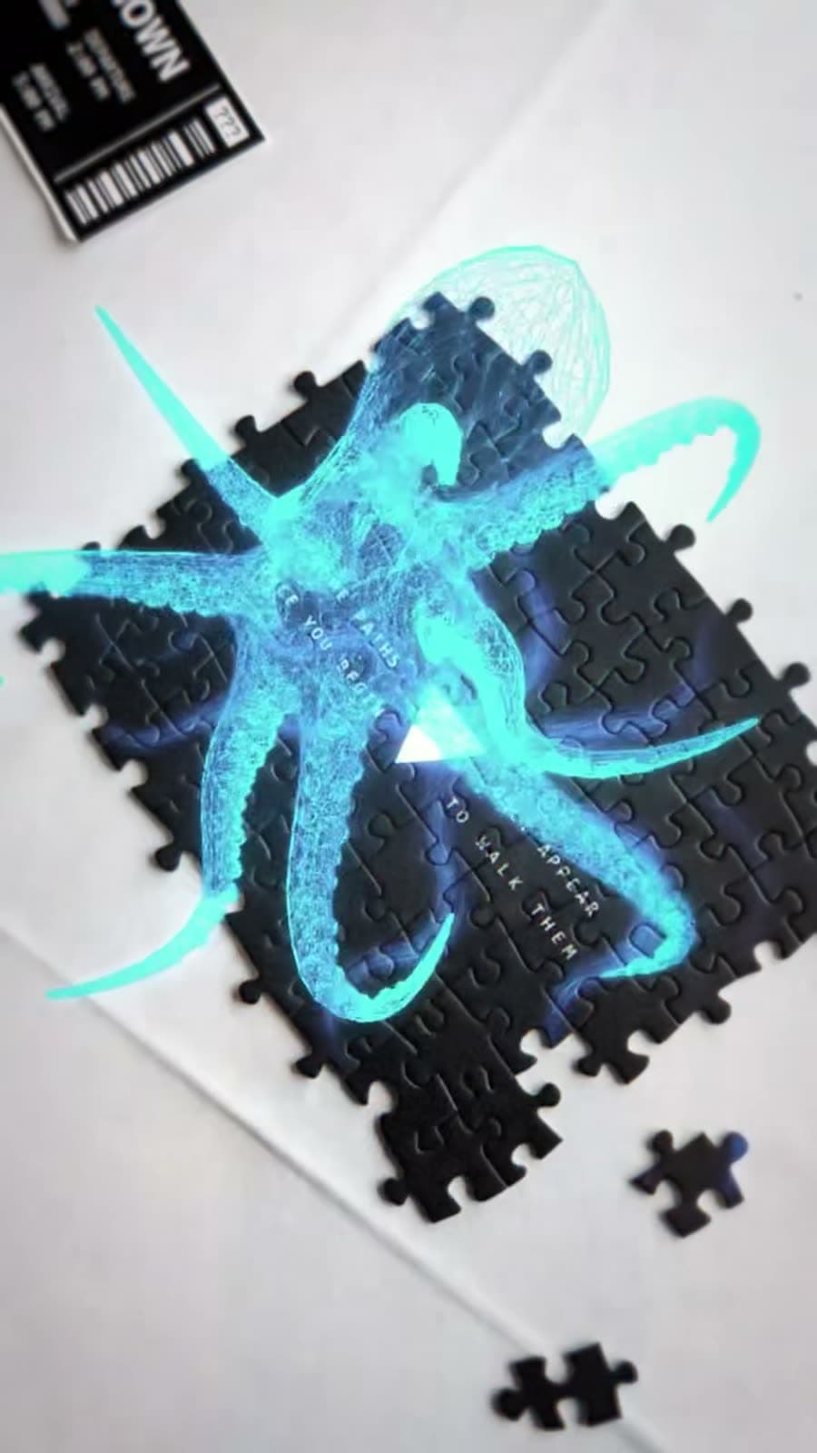 A completed jigsaw on a white table with a glowing augmented-reality octopus rising out of it